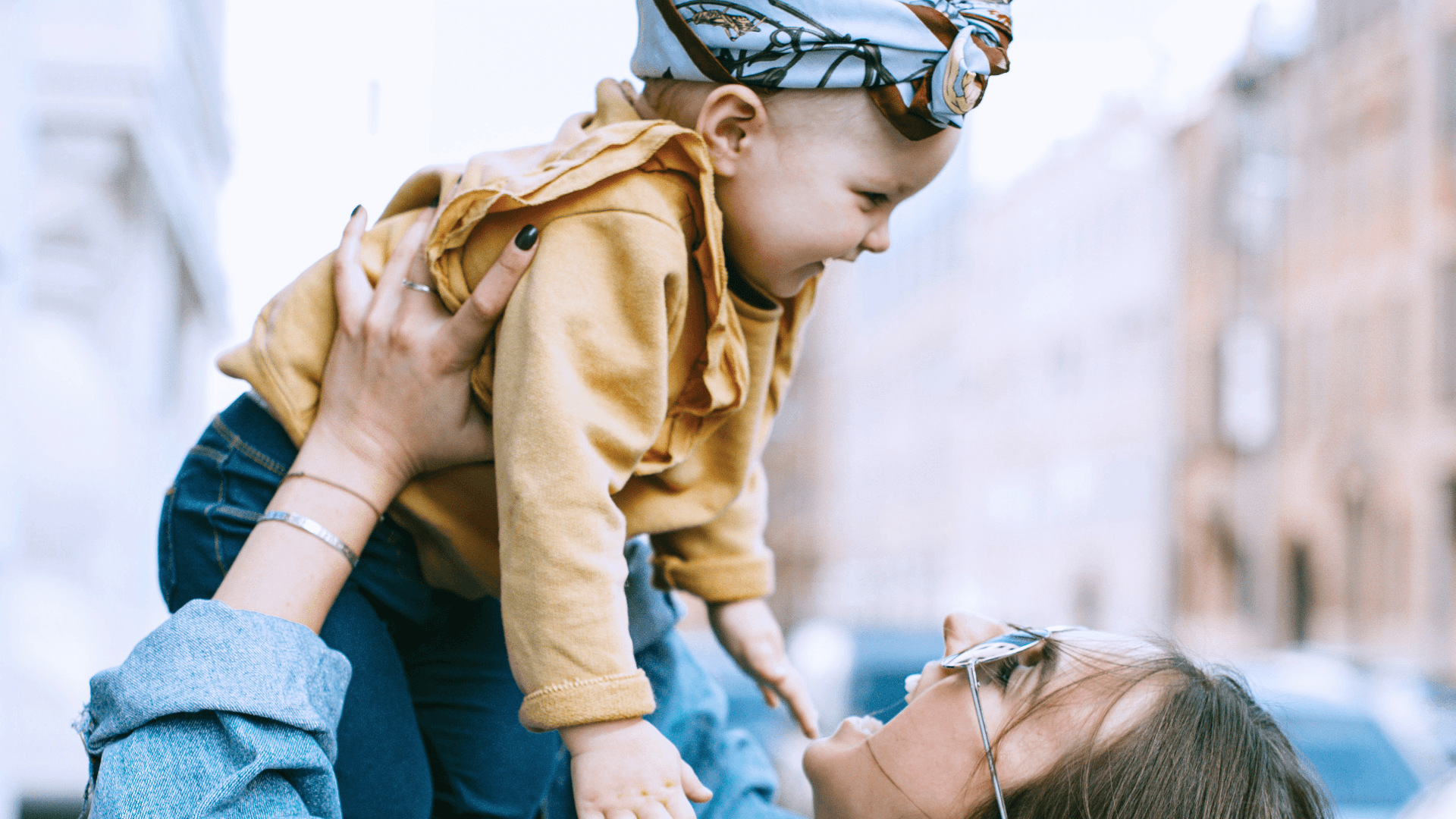 Woman smiling while lifting up a baby