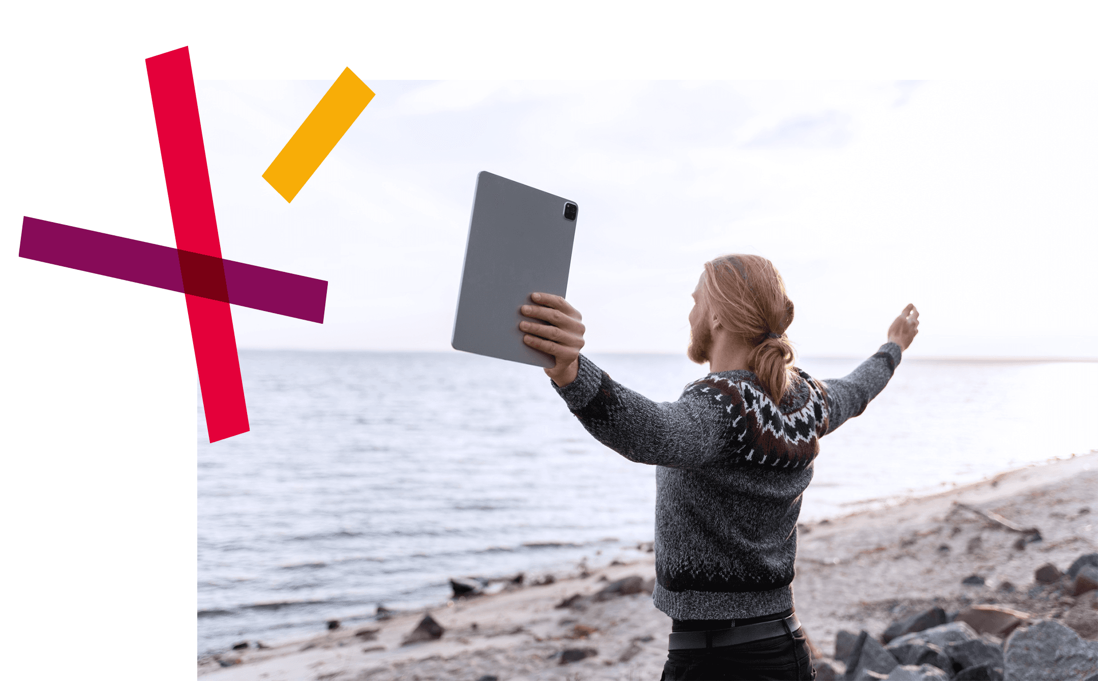 Man holding a tablet, standing in front of the ocean