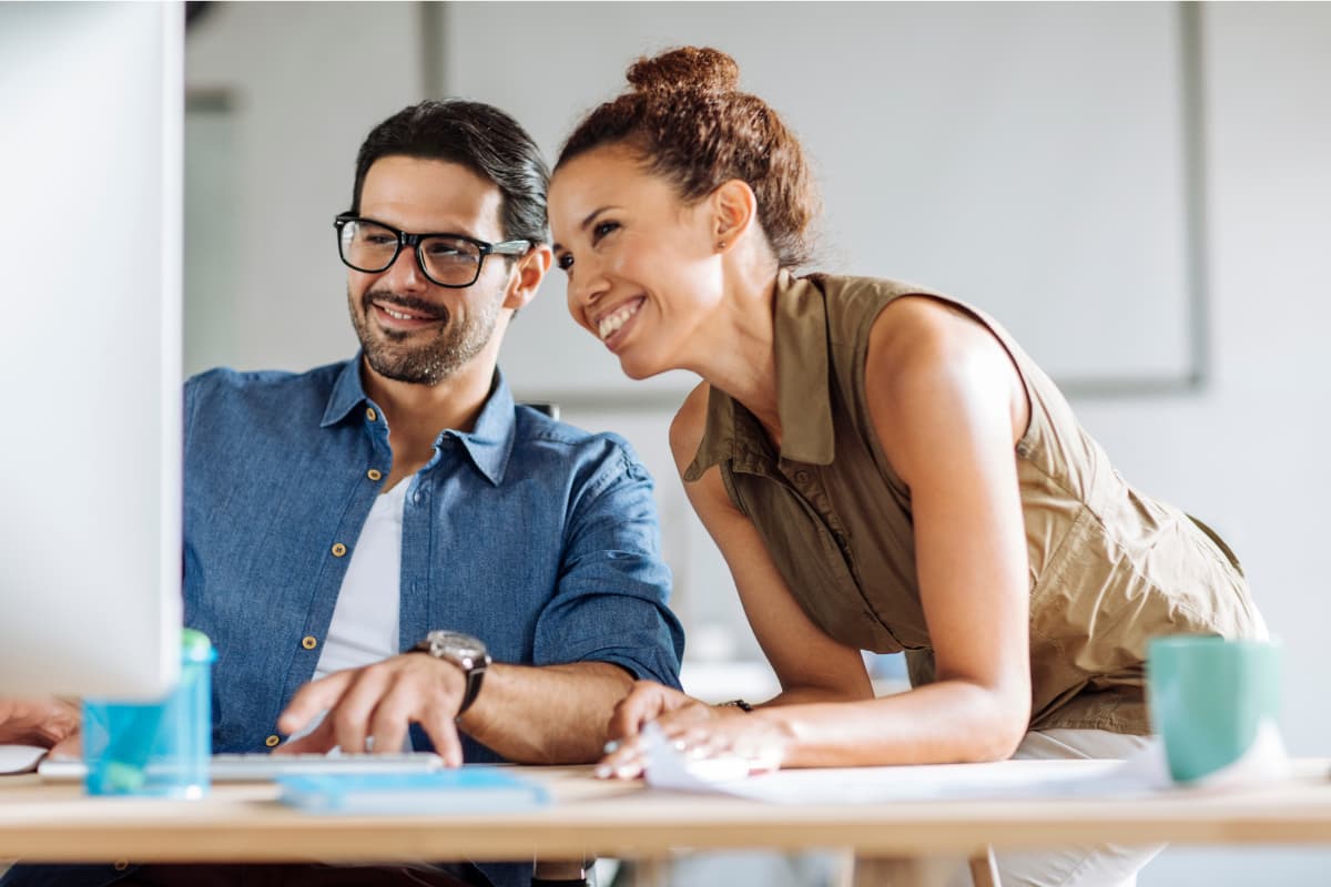 En man och en kvinna som ler framför en skärm